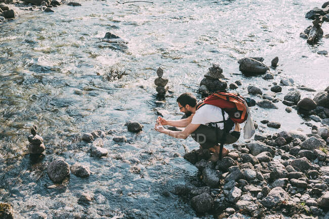 Male boulderer photographing river, Lombardy, Italy — Stock Photo