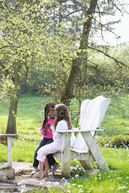 Meninas falando em uma cadeira em um jardim — Fotografia de Stock