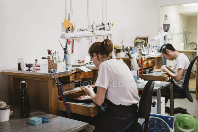Female and male jewellers working at workbench — Stock Photo