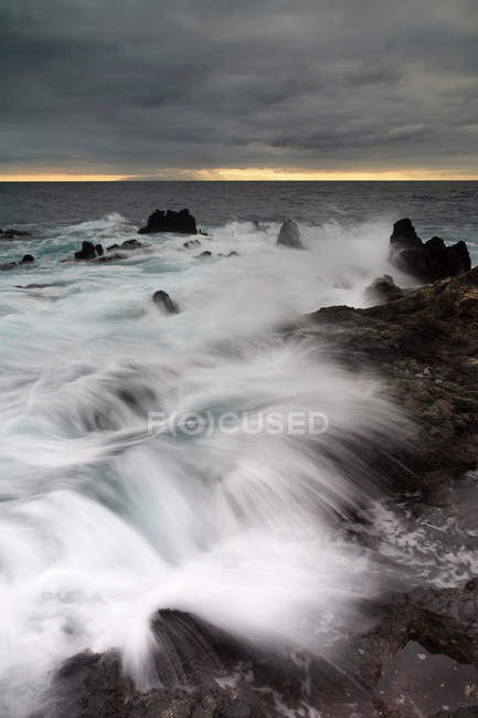 Time lapse vista de las olas en la playa rocosa - foto de stock