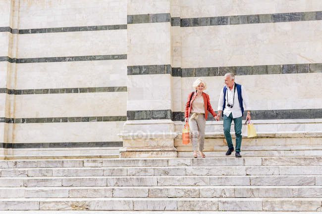 Tourist couple moving down Siena cathedral stairway, Tuscany, Italy — Stock Photo