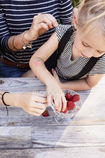 Mãe e filha tendo morangos no jardim — Fotografia de Stock