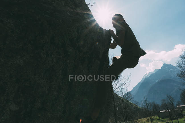 Vista retroilluminata del giovane maschio che si arrampica sul masso — Foto stock