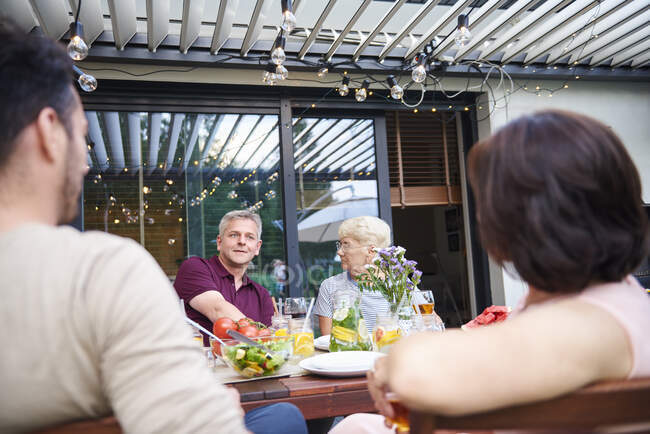 Вид на плечо пожилой женщины и взрослого мужчины за семейным обедом на патио — стоковое фото