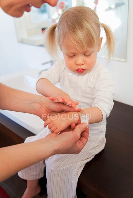 Mother putting bandage on toddler girl — Stock Photo