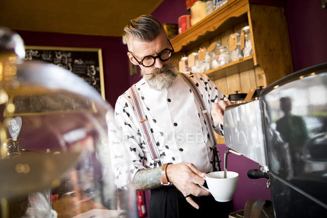 Seniorchef bereitet Kaffee hinter Café-Theke zu — Stockfoto