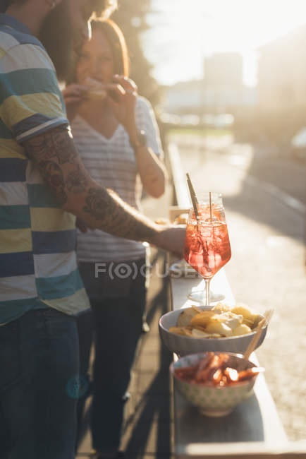 Casal comendo tapas no café da calçada iluminado pelo sol — Fotografia de Stock