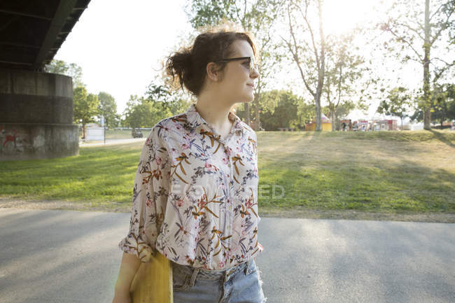 Mujer joven que lleva monopatín al aire libre - foto de stock