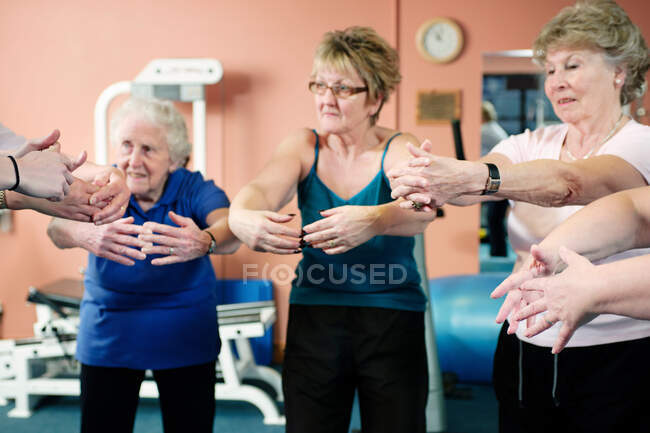 Las mujeres mayores estirándose en el gimnasio - foto de stock