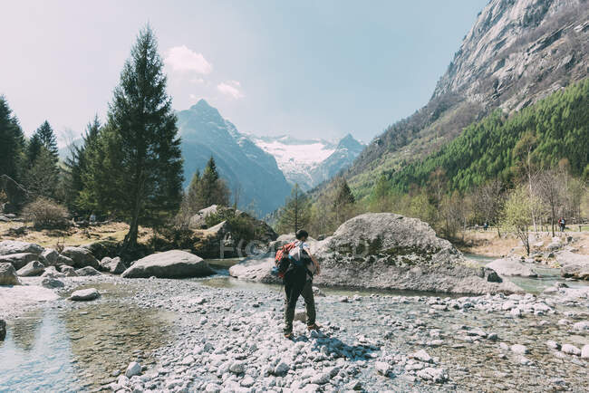 Vue arrière du rocher mâle debout près de la rivière de la vallée, Lombardie, Italie — Photo de stock
