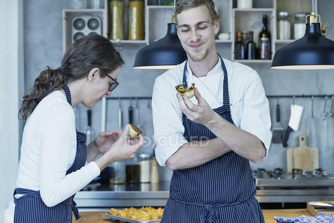 Two chefs in kitchen tasting freshly baked canapes — Stock Photo