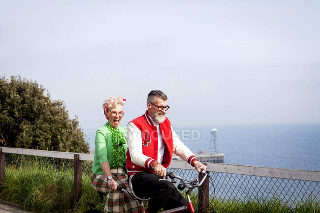 Quirky couple sightseeing on tandem bicycle, Bournemouth, England — Stock Photo