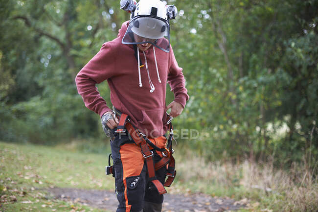 Young male trainee tree surgeon fastening safety harness — Stock Photo
