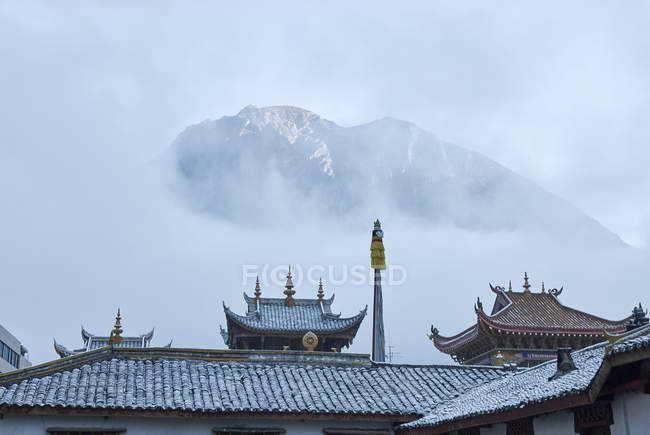 Крыши храма Цзинган и туманные горы, Кандин, Сычуань, Китай — стоковое фото