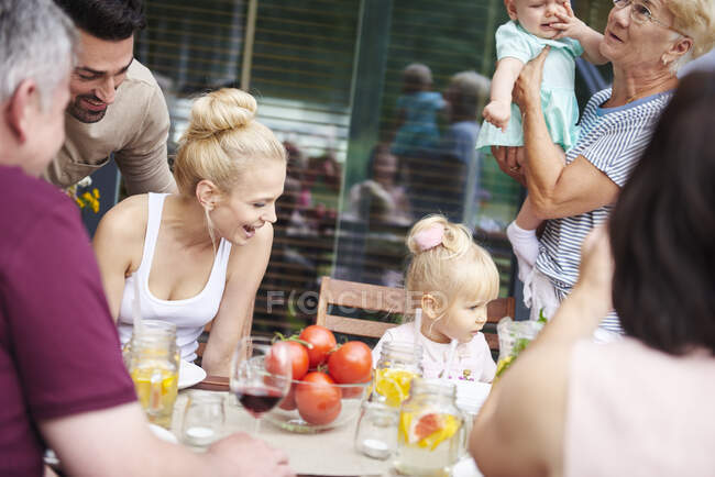 Família de três gerações com bebê menina e criança feminina no almoço de família na mesa do pátio — Fotografia de Stock