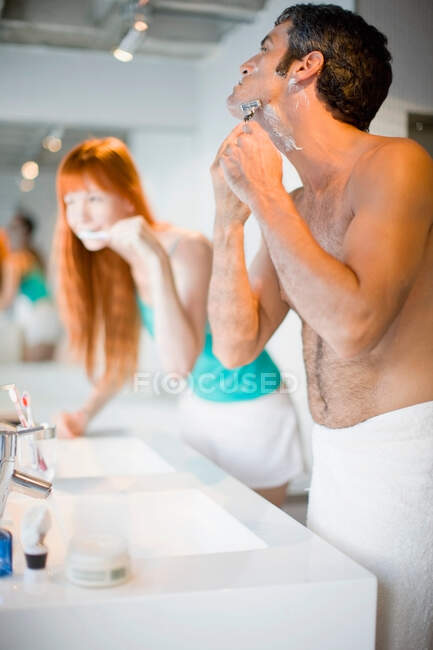 Couple brushing teeth and shaving — Stock Photo