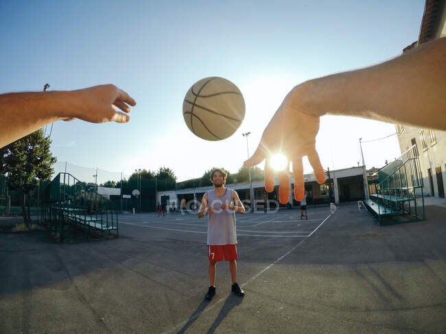 Punto de vista imagen del hombre lanzando baloncesto a su compañero de equipo - foto de stock