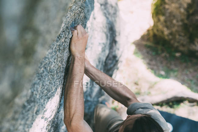 Высокий угол обзора молодого человека, карабкающегося по камню — стоковое фото