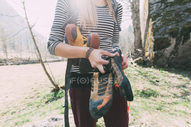 Sección media del roquero femenino sosteniendo zapatos de escalada, Lombardía, Italia - foto de stock