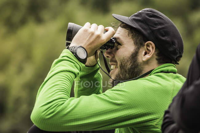 Mochilero joven mirando binoculares en el Parque Nacional Queulat, Chile - foto de stock