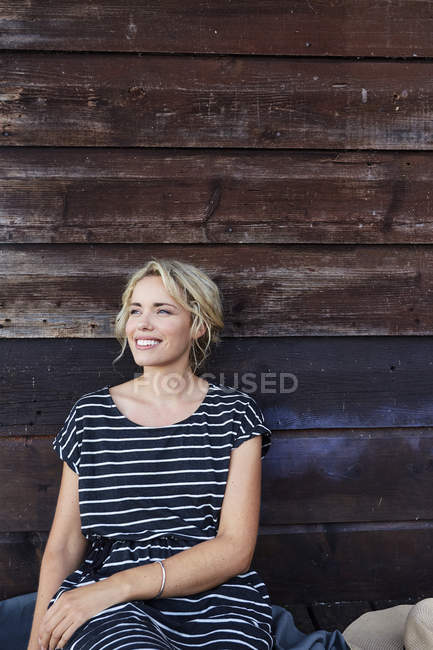 Woman sitting against wooden building — Stock Photo