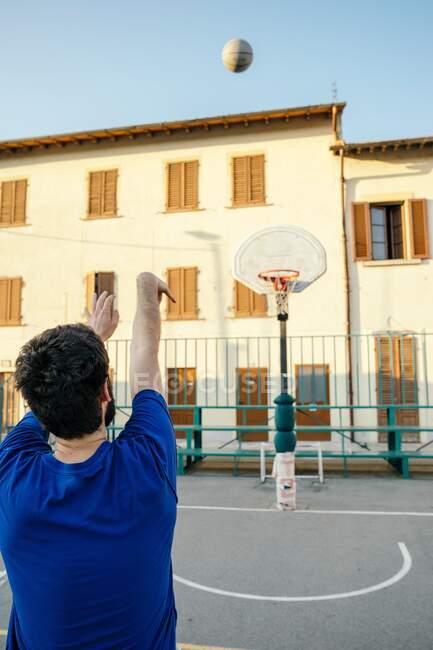 Visão traseira do homem jogando basquete no aro de basquete — Fotografia de Stock