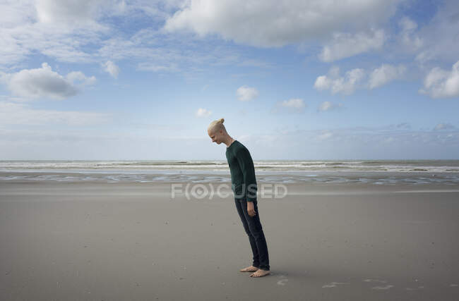 Ragazzo in piedi sulla spiaggia, inclinato in avanti nel vento tempestoso, Gravelines, Nord-Pas-de-Calais, Francia — Foto stock