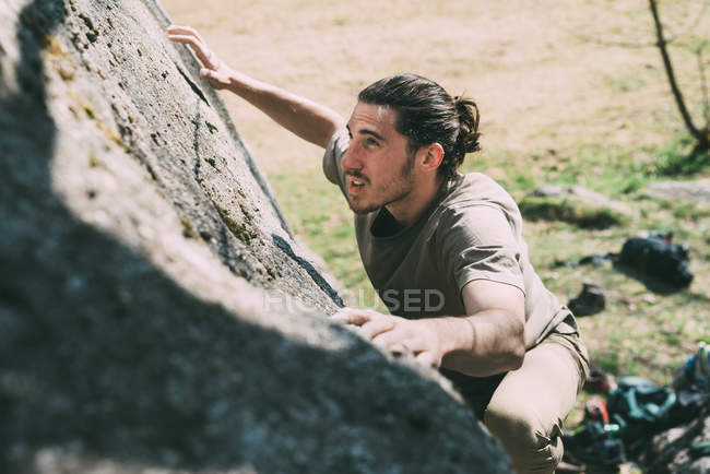 Young man climbing up on boulder — Stock Photo