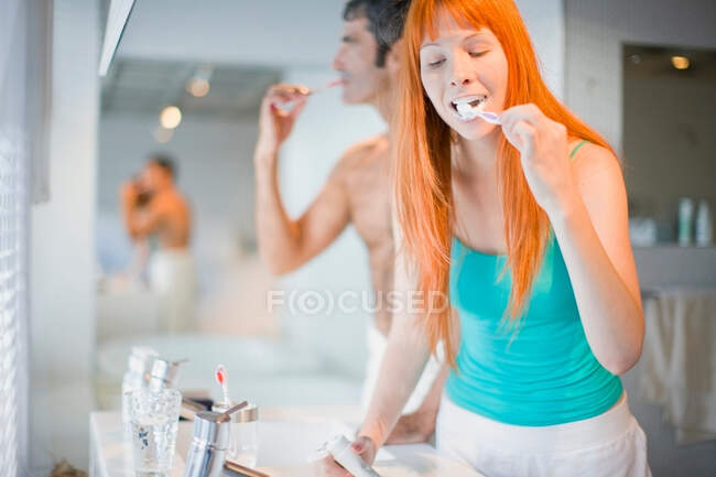 Pareja cepillándose los dientes en el baño - foto de stock
