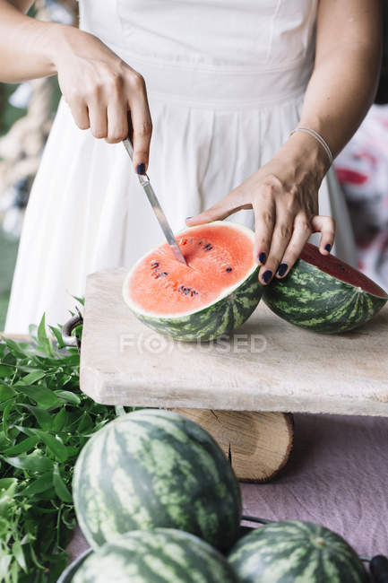 Frau schneidet Wassermelone auf Schneidebrett — Stockfoto