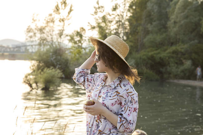 Jeune femme en chapeau de paille au bord du lac — Photo de stock