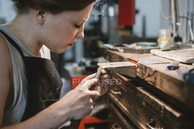 Juwelierin arbeitet mit Feilenwerkzeug an Werkbank — Stockfoto