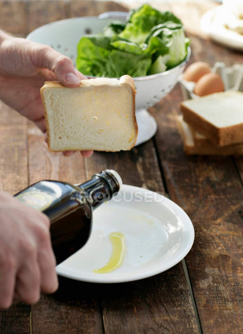 Uomo versando olio d'oliva sul piatto — Foto stock