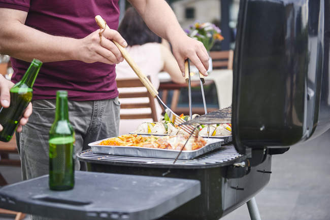 Mid section of man barbecuing on patio at family lunch — Stock Photo
