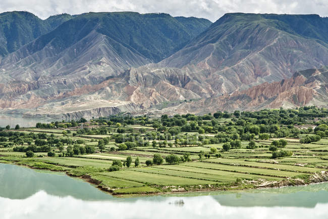 Vista elevada de las montañas y tierras agrícolas por el río Amarillo, Sichuan, China - foto de stock