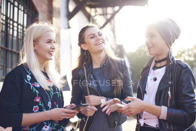 Tre giovani amiche chiacchiere sulla strada della città illuminata dal sole — Foto stock