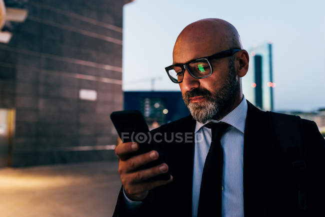 Homem de negócios maduro usando smartphone à noite — Fotografia de Stock