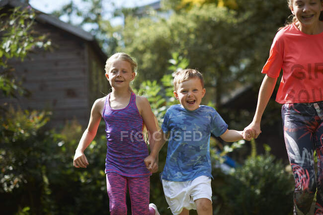 Siblings holding hands running in garden — Stock Photo