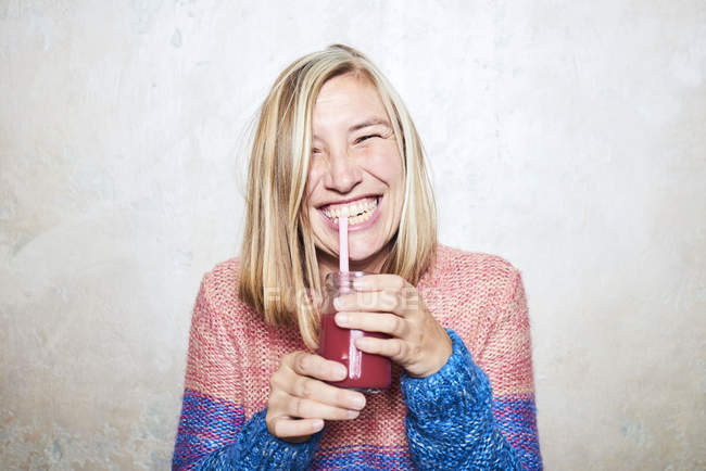 Portrait of woman drinking smoothie, smiling — Stock Photo