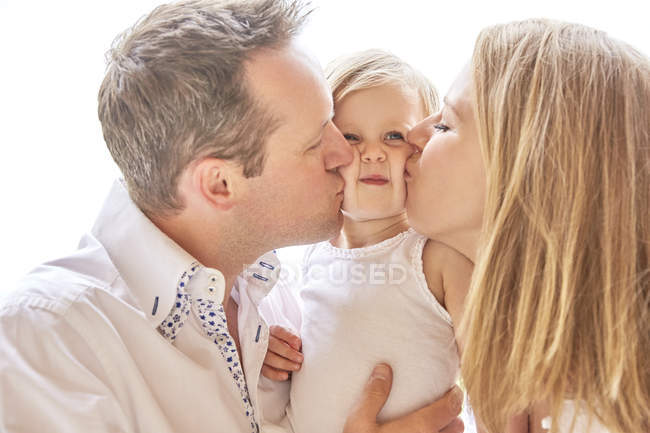 Portrait of couple kissing baby daughter — Stock Photo