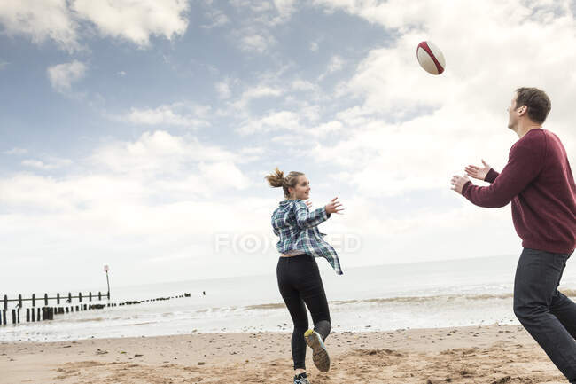 Padre e hija jugando rugby en la playa - foto de stock