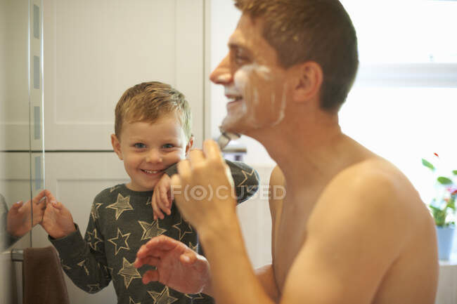 Portrait of boy in bathroom with father shaving — Stock Photo