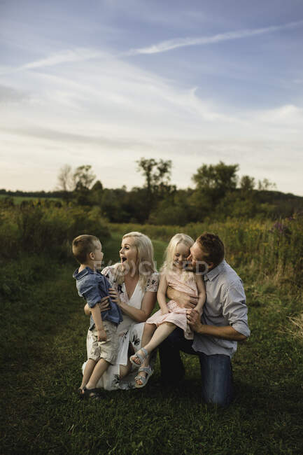 Padres sonrientes abrazando a los niños en el área rural - foto de stock