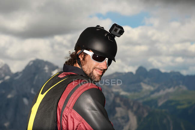 Retrato de puente de base con traje de ala con cámara de acción en el casco, montañas Dolomita, Canazei, Trentino Alto Adige, Italia, Europa - foto de stock