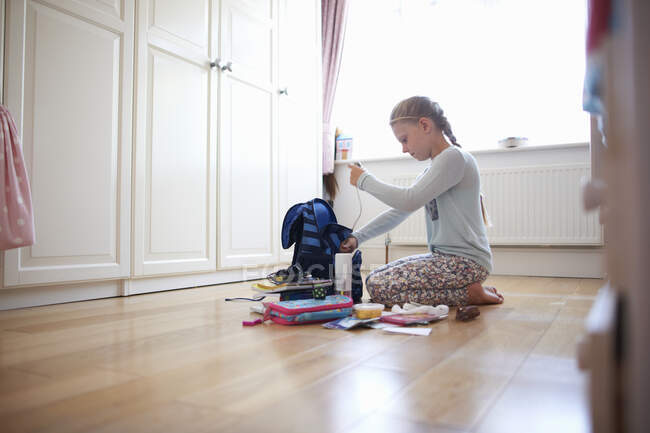 Mädchen kniet auf dem Boden und packt Schultasche — Stockfoto