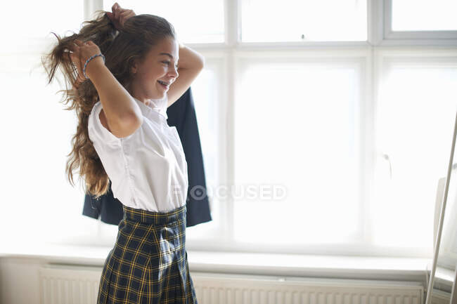 Teenage schoolgirl styling long hair in bedroom — Stock Photo