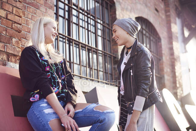 Dos amigas jóvenes charlando en la calle de la ciudad - foto de stock
