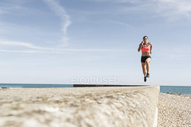 Молода жінка біжить уздовж морської стіни — стокове фото