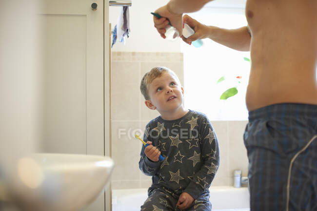 Menino no banheiro com o pai se preparando para escovar os dentes — Fotografia de Stock