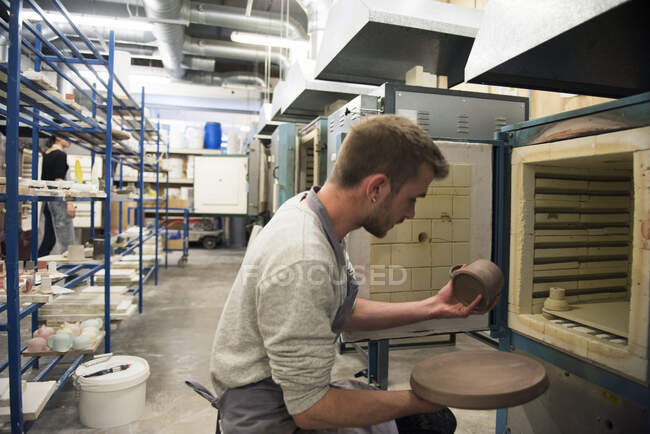 Uomo che rimuove la ceramica dal forno — Foto stock